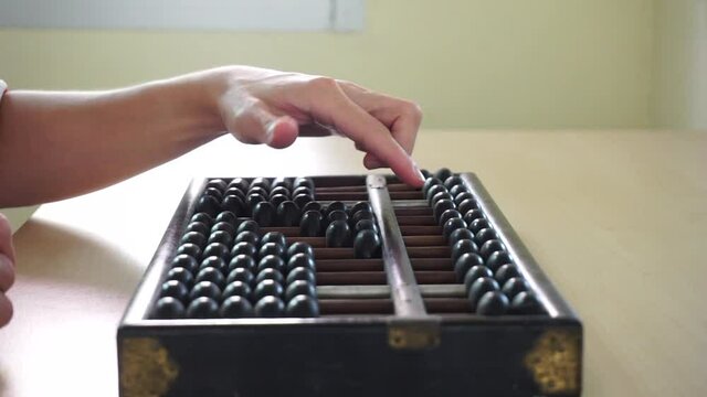 close up of a person using a vintage abacus with left hand