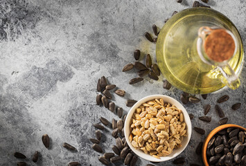 Sunflower seeds in a bowl with cooking oil on concrete background. Concept of food industry.