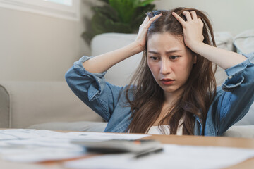 young asian woman cover her head after stressed with monthly bill expenses and credit card debt.