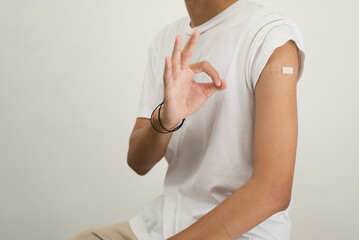 Happy Asian man showing his arm and bandage after they get a vaccine.