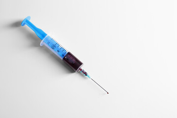 Fototapeta premium Plastic syringe with blood on white background