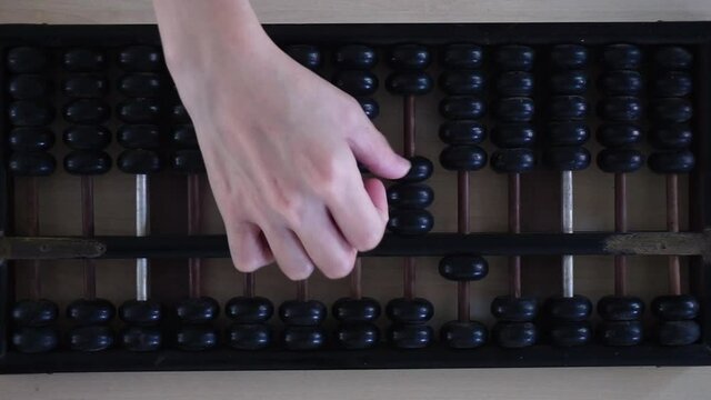 Top view of hand of a person using black abacus with right hand