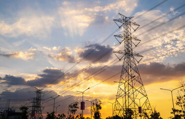 Silhouette of high voltage electric pole structure on sunset time with blue and orange sky. There is some sunlight through the clouds. Electric and transformer concept. Sunset with yellow light.