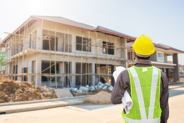 Fototapeta premium young professional engineer in protective helmet and blueprints paper at the house building construction site