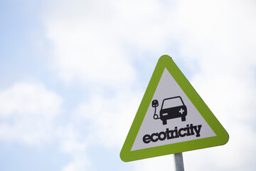 A sign denoting a charging point for electric vehicles against a light blue sky
