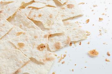 Dry flat bread broken in pieces and divided, with crumbs, on white background, Croatian traditional...