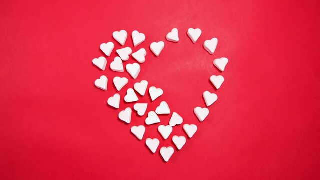 Marshmallows in the form of a heart on a red background. Valentine's day concept. Stop motion animation.