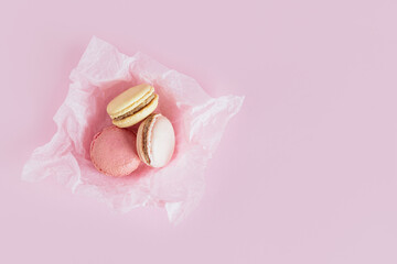 Tasty french macaroons on a pink pastel background.