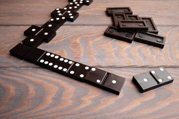 Black dominoes lie on a wooden table, top view. Board game.