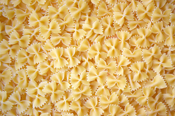 A lot of pasta in the shape of a butterfly on the table as a background.