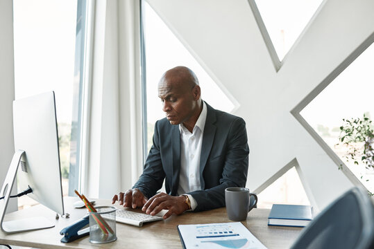 Focused black male businessman typing on computer - Powered by Adobe