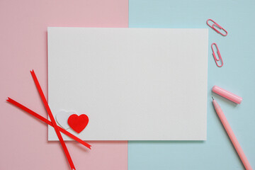 Greeting card idea for Valentine's Day, horizontal white card placed on pastel blue and pink paper and pink pen with small red and white hearts.flat lay,top view.copy space.