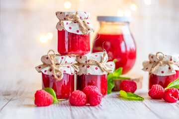 Raspberry marmalade in small glasses is placed on wooden desk. Homemade jam from fresh raspberries. Fresh and healthy cooking.
