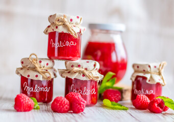 Raspberry marmalade in small glasses is placed on wooden desk. Homemade jam from fresh raspberries. Fresh and healthy cooking. Translation for "Malina" is "Raspberry"