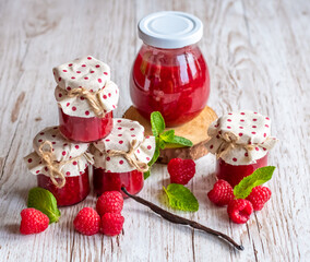 Raspberry marmalade in small glasses is placed on wooden desk. Homemade jam from fresh raspberries. Fresh and healthy cooking.