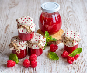 Raspberry marmalade in small glasses is placed on wooden desk. Homemade jam from fresh raspberries. Fresh and healthy cooking.