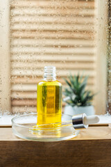 Open glass bottle with body and face oil on a wooden shelf in the bathroom. Care cosmetics and serum for the face.