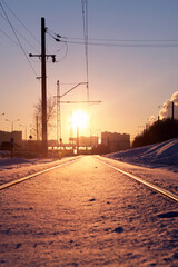 Beautiful snow-covered railway in the rays of the setting sun. The rails are heavily covered in snow.