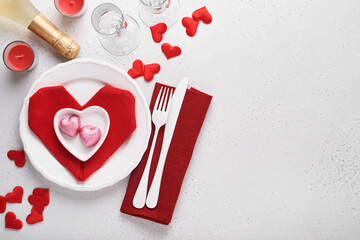 Valentinas day table setting white color with white silverware, red napkin folded as heart, candles, champagne, glasses on white background for greetings. Romantic dinner or menu concept. Mock up.