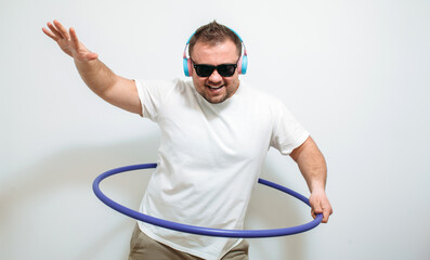 Funny image of a fat guy in headphones spinning a hula hoop on white background. Fitness time. Time...