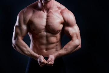 Fototapeta na wymiar Professional bodybuilder posing over isolated black background. Studio shot of a fitness trainer flexing the muscles in an aggressive pose. Close up, copy space.