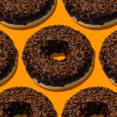delicious donuts with dark chocolate isolated on orange background