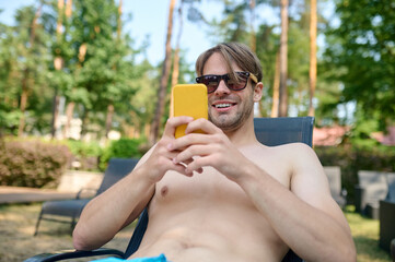 A young man in sunglasses with a smartphone in hands