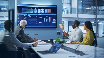 Multi-Ethnic Office Conference Room Meeting: Diverse Team of Professional Entrepreneurs, Investors Talk, Use TV Screen with infographics, Charts, Graphs. Businesspeople Discuss Investment Strategy