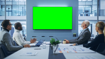 Office Conference Room Meeting using Video Call: Diverse Team of Successful Managers, Executives Talk, Use Green Screen Chroma Key TV. Businesspeople Work on Strategy for an e-Commerce Startup