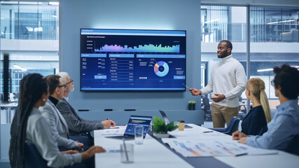 Office Conference Room Meeting Presentation: Black Businessman Talks, Uses TV Screen to Show Company Growth with Big Data Analysis, Graphs, Charts, Infographics. e-Commerce e-Business. - obrazy, fototapety, plakaty