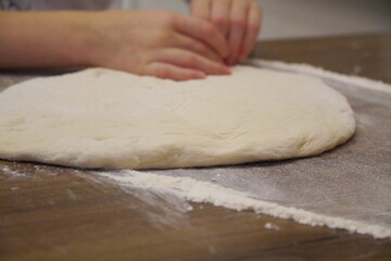 Young hands knead the dough