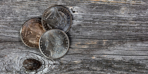 Collection of US Morgan silver dollars with patina finish on weathered wooden boards