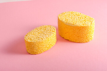 yellow oval sponge for washing the face on a pink background. Copy space for text