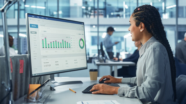 Corporate Office: Black Female IT Technician Using Desktop Computer with Big Data Statistics, Graphs. Smiling Creative Software Engineer Work on eCommerce Project Marketing, Development.