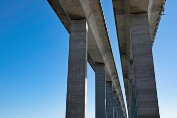 Two-lane expressway bridge with tall pillars against a blue sky, with copy space.