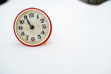 Old mechanical alarm clock in the snow, on a winter day. Copy space.