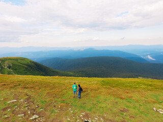 Aerial view of the Great Green Ridge. Guy and Girl Standing on a Big Hill against the Backdrop of a Huge Mountain Landscape