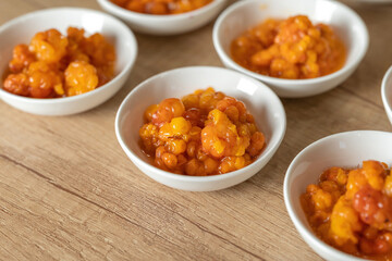 Juicy ripe cloudberry northern in a plate. Many plates on the table.
