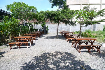Table Decoration in the Open Garden and Long Chairs and Trees with Shady Plants in the Sun in a Restaurant