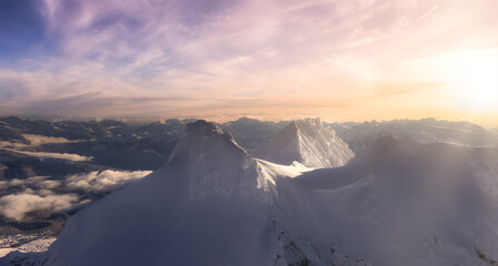 Aerial Panoramic View of Canadian Mountain covered in snow. Colorful sunset Sky Art Render. Located near Squamish, North of Vancouver, British Columbia, Canada. Nature Background Panorama