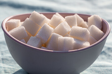 Cubic sugar lumps are in the brown bowl