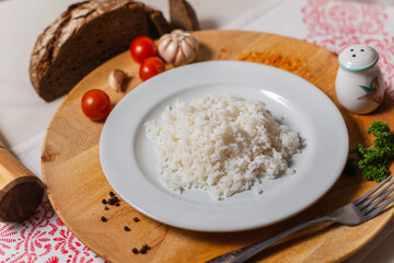 a portion of boiled rice in a white plate on a wooden background
