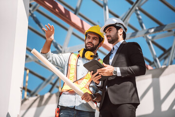 Civil engineer and construction worker manager holding digital tablet and blueprints , talking and...