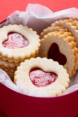 Red box with heart shaped linzer cookies on red background. Mother's day, Women's day, Valentine's day. Homemade present. Copy space, top view. Selective focus.