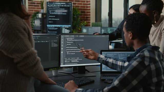 Software developers discussing about source code compiling discovers errors and asks the rest of the team for explanations in front of multiple screens running algorithms. Programmers doing teamwork.