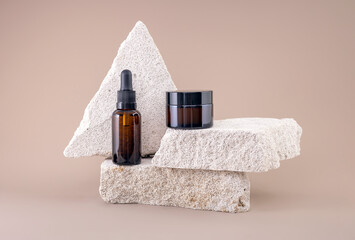 glass containers for natural cosmetics on a podium made of stones on a brown background