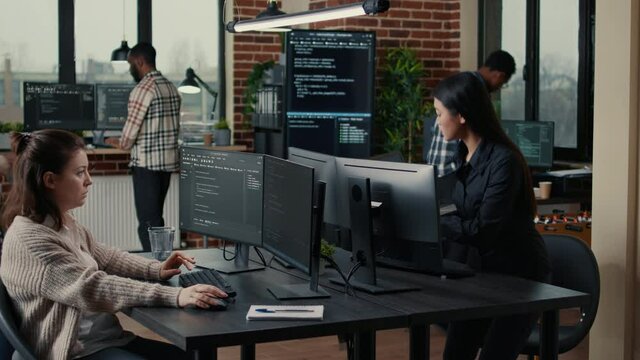 Software engineer typing source code on computer keyboard while colleagues sit down at desk for group project. App developer working in it startup company doing online cloud computing.