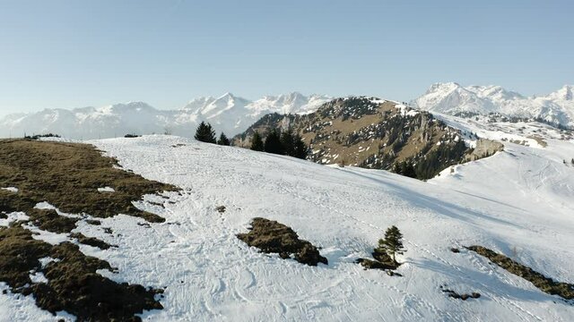 Push in Shot of Melting Snow on Top of the Hill, Revealing Rare Spruce Forest, Big Rocks, Hiking Road With Footprints, Sleigh, Ski Lines and Alps in The Background. Reminding of Edoras.