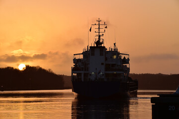 Fototapeta premium Frachtschiff im Nord-Ostsee-Kanal bei Sonnenuntergang 