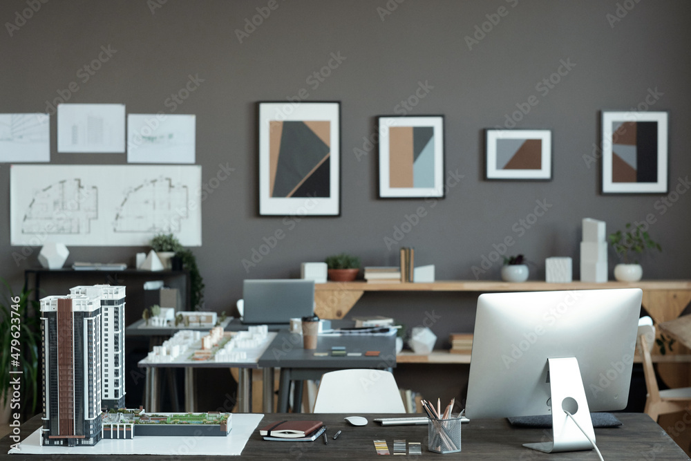 Poster layout of block of flats, computer monitor and other supplies on workplace of contemporary architect